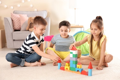 Cute little children playing with building blocks on floor, indoors