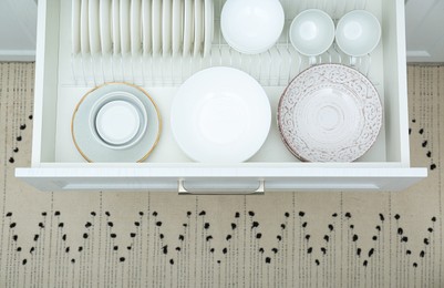 Photo of Open drawer with different plates and bowls in kitchen, above view
