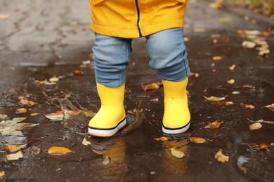 Little girl walking in puddle outdoors, closeup