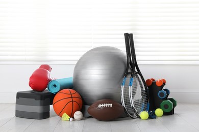 Set of different sports equipment on white floor indoors