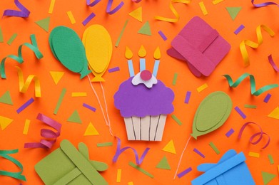 Photo of Birthday party. Paper cupcake, air balloons and gifts on orange background, flat lay