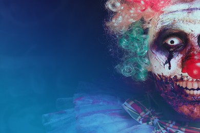 Terrifying clown on dark background, closeup with space for text. Halloween party costume