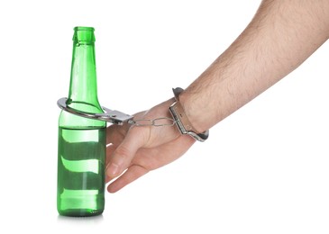 Man in handcuffs with bottle of beer on white background, closeup. Alcohol addiction
