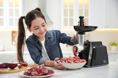 Little girl using modern meat grinder in kitchen
