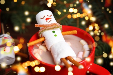 Funny marshmallow snowman in cup of hot drink. Bokeh effect 