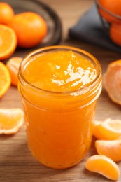 Photo of Delicious tangerine jam on wooden table, closeup