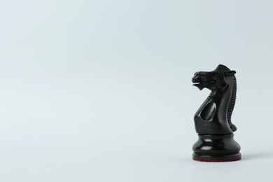 Black knight on light background, space for text. Chess piece