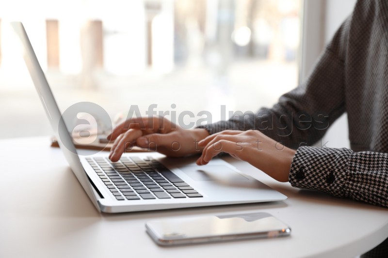 Young blogger working with laptop at table indoors, closeup