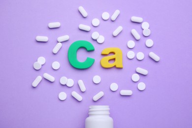Symbol Ca (Calcium), medical bottle and pills on violet background, top view