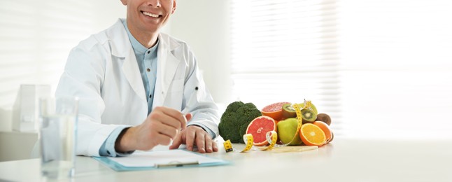 Nutritionist at desk in his office, closeup. Banner design