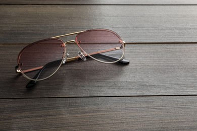 New stylish sunglasses on wooden table, space for text