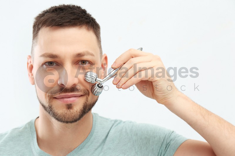 Photo of Man using metal facial roller on white background