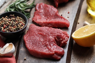 Fresh raw meat steaks and spices on wooden table, closeup