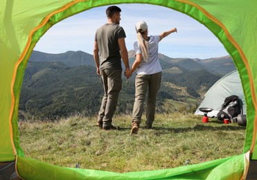 Photo of Couple in mountains on sunny day, view from camping tent