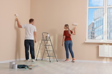 Photo of Couple painting wall in apartment during repair