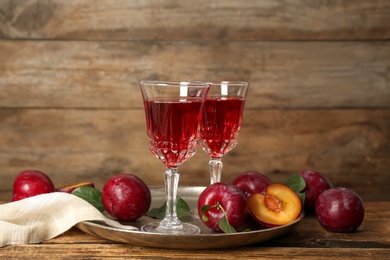Delicious plum liquor and ripe fruits on wooden table. Homemade strong alcoholic beverage