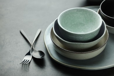 Photo of Set of stylish empty dishware and cutlery on grey table, closeup