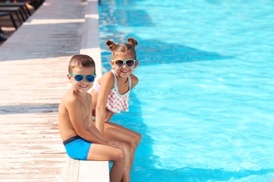 Cute little children sitting near swimming pool