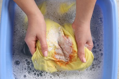 Woman washing garment with stain, top view