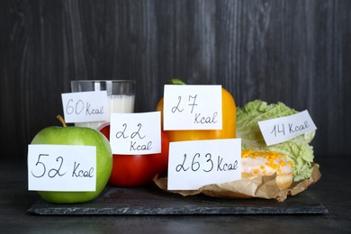 Food products with calorific value tags on black table. Weight loss concept