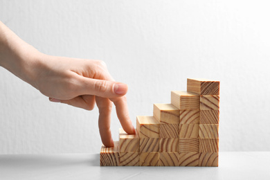 Photo of Woman and staircase made with wooden cubes on white background, closeup. Career promotion concept