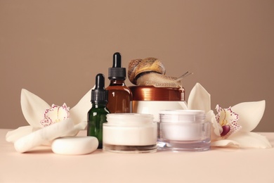 Organic cosmetics made with mucin, snail, spa stones and beautiful flowers on table