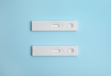 Two disposable express tests for hepatitis on light blue background, flat lay