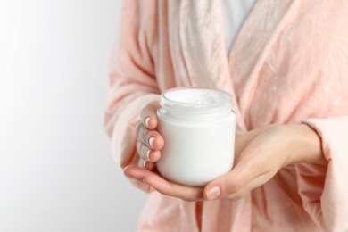 Photo of Woman holding jar of hand cream on white background, closeup. Space for text