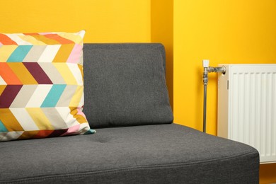 Bright cushion on grey sofa in room