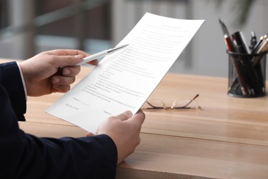 Man reading document at table in office, closeup. Signing contract