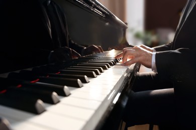 Man playing piano indoors, closeup. Talented musician