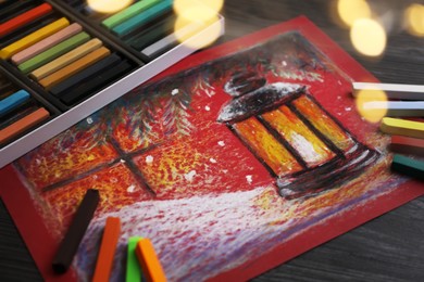 Colorful chalk pastels and beautiful painting on black wooden table. Bokeh effect