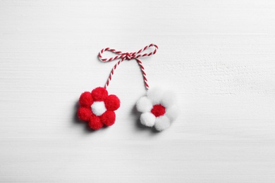 Photo of Traditional martisor with flowers on white wooden background, top view. Beginning of spring celebration