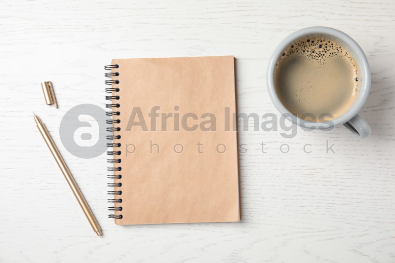 Notebook and cup of coffee on wooden background, top view