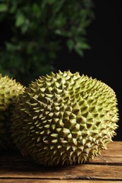 Ripe durians on wooden table against blurred background. Space for text