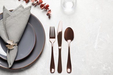 Photo of Plates with fabric napkin, decorative ring and cutlery on light gray marble table, flat lay