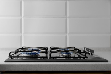Photo of Gas cooktop with burning blue flames in kitchen