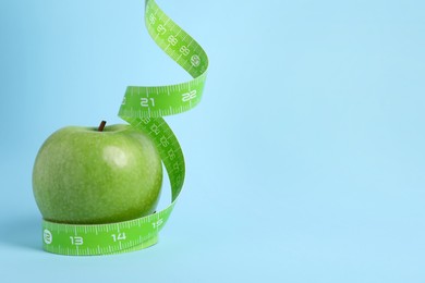 Ripe green apple and measuring tape on light blue background. Space for text