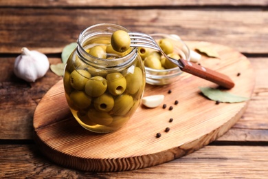 Glass jar of pickled olives on wooden table