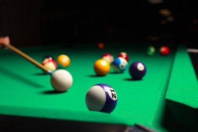 Photo of Many colorful billiard balls and cue on green table, closeup. Space for text