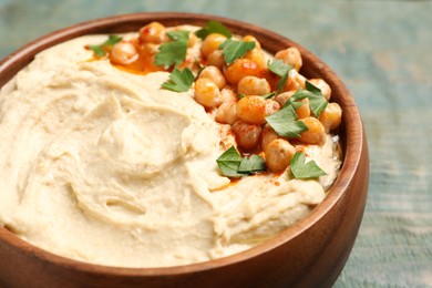Photo of Bowl of tasty hummus with chickpeas and parsley on wooden table, closeup
