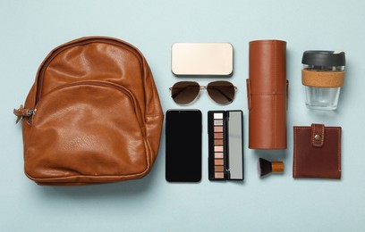 Stylish urban backpack with different items on light background, flat lay