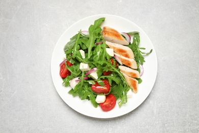 Delicious salad with meat, arugula and vegetables on grey table, top view