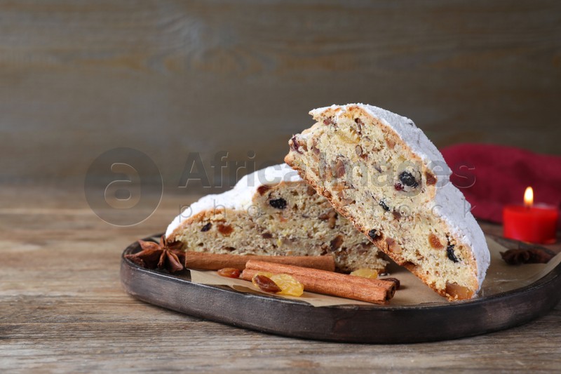 Plate of cut delicious Stollen sprinkled with powdered sugar and ingredients on wooden table