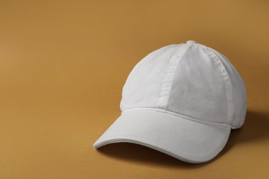 Baseball cap on brown background, space for text