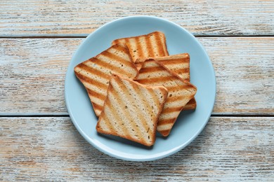Plate with slices of delicious toasted bread on wooden table, top view