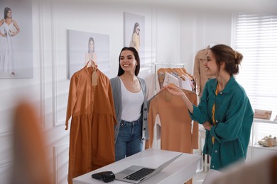 Photo of Young woman buying clothes in modern boutique
