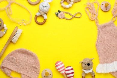 Photo of Frame of baby clothes and accessories on yellow background, flat lay. Space for text