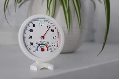 Round mechanical hygrometer on white table indoors. Space for text