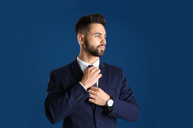Portrait of handsome young man in office suit on color background